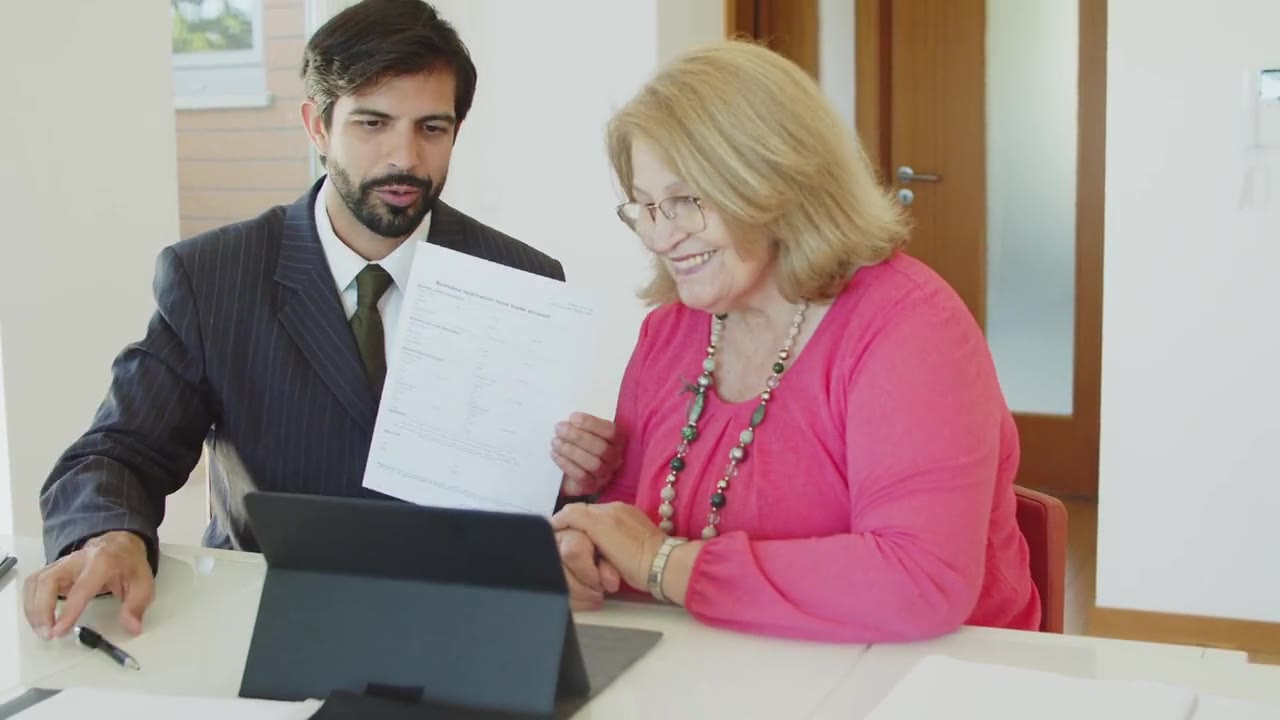An advisor walks a client through numbers on a tablet at a desk.